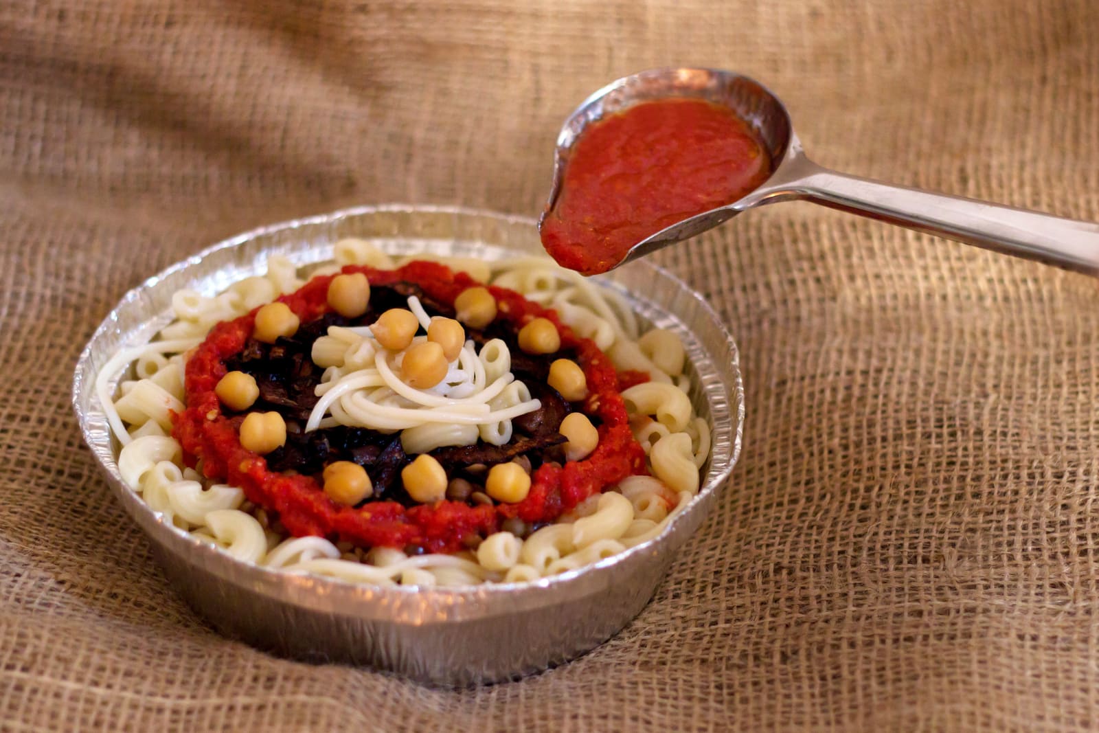 A bowl of Egyptian koshari with tomato sauce